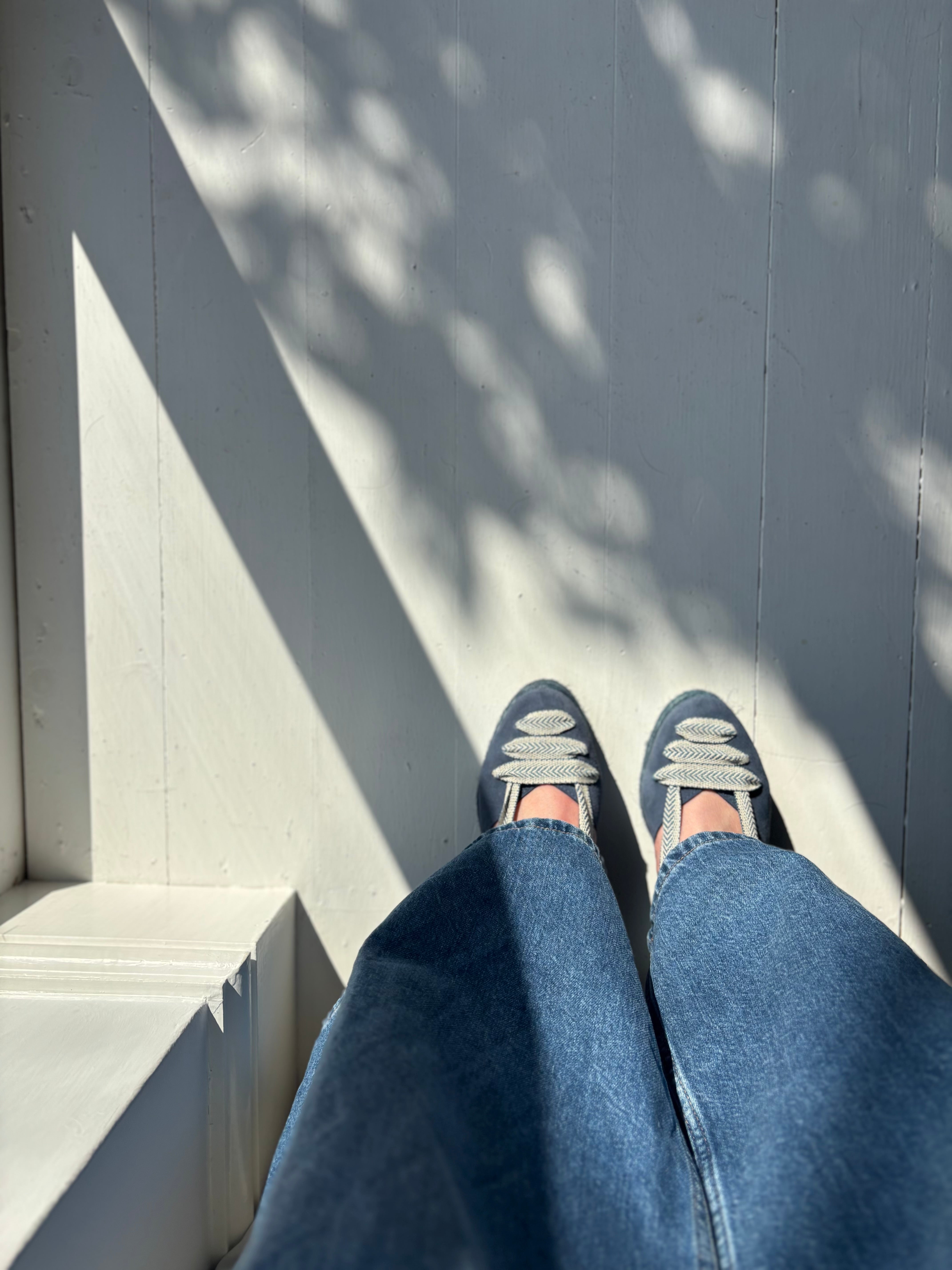 Blue and white shoes on a white wooden floor, worn with jeans.