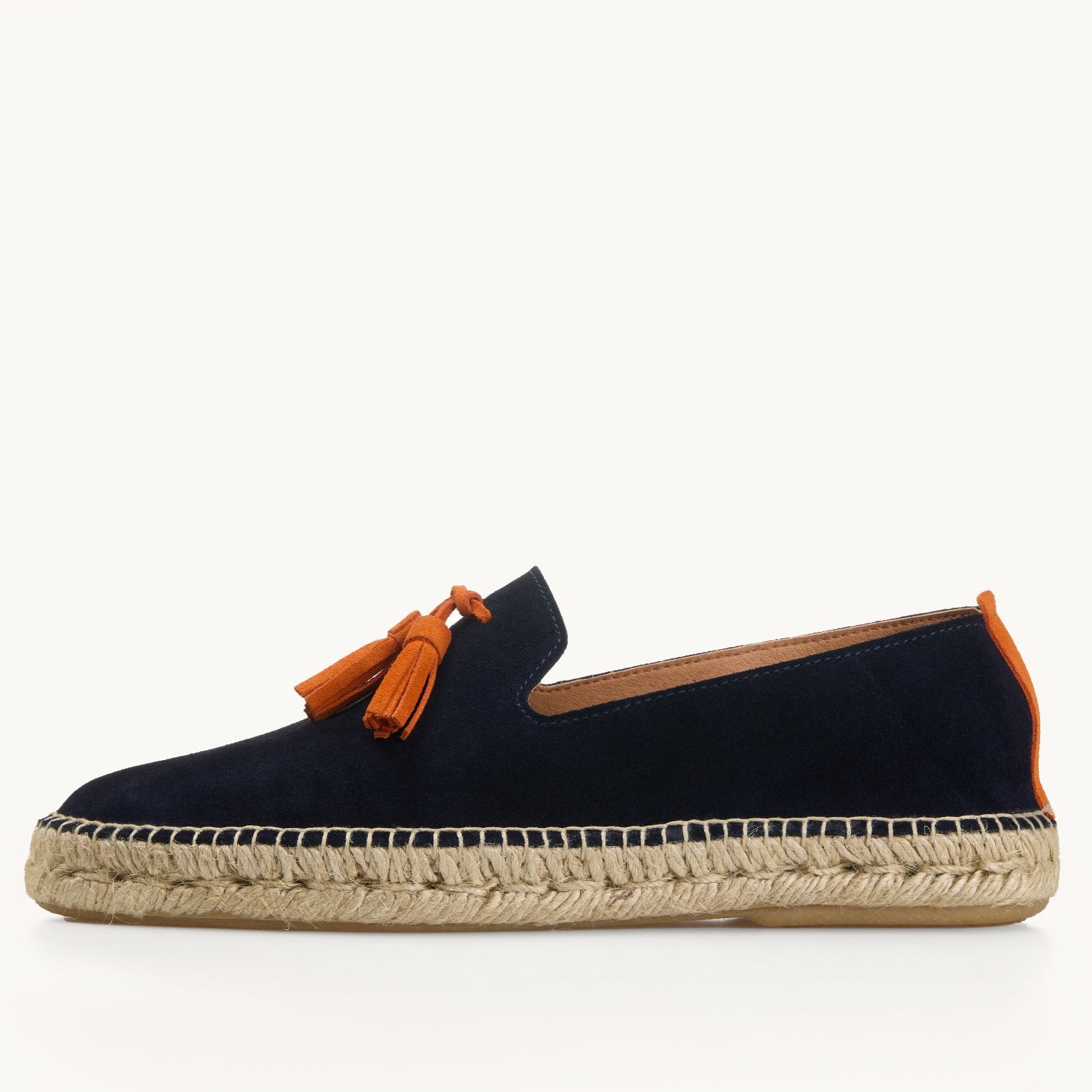 One men's navy blue suede loafer. Jute sole. Neck opening of the espadrille has a narrow tan edged inside the shoe. Two orange suede tassel on the front and orange suede stripe up the heel.