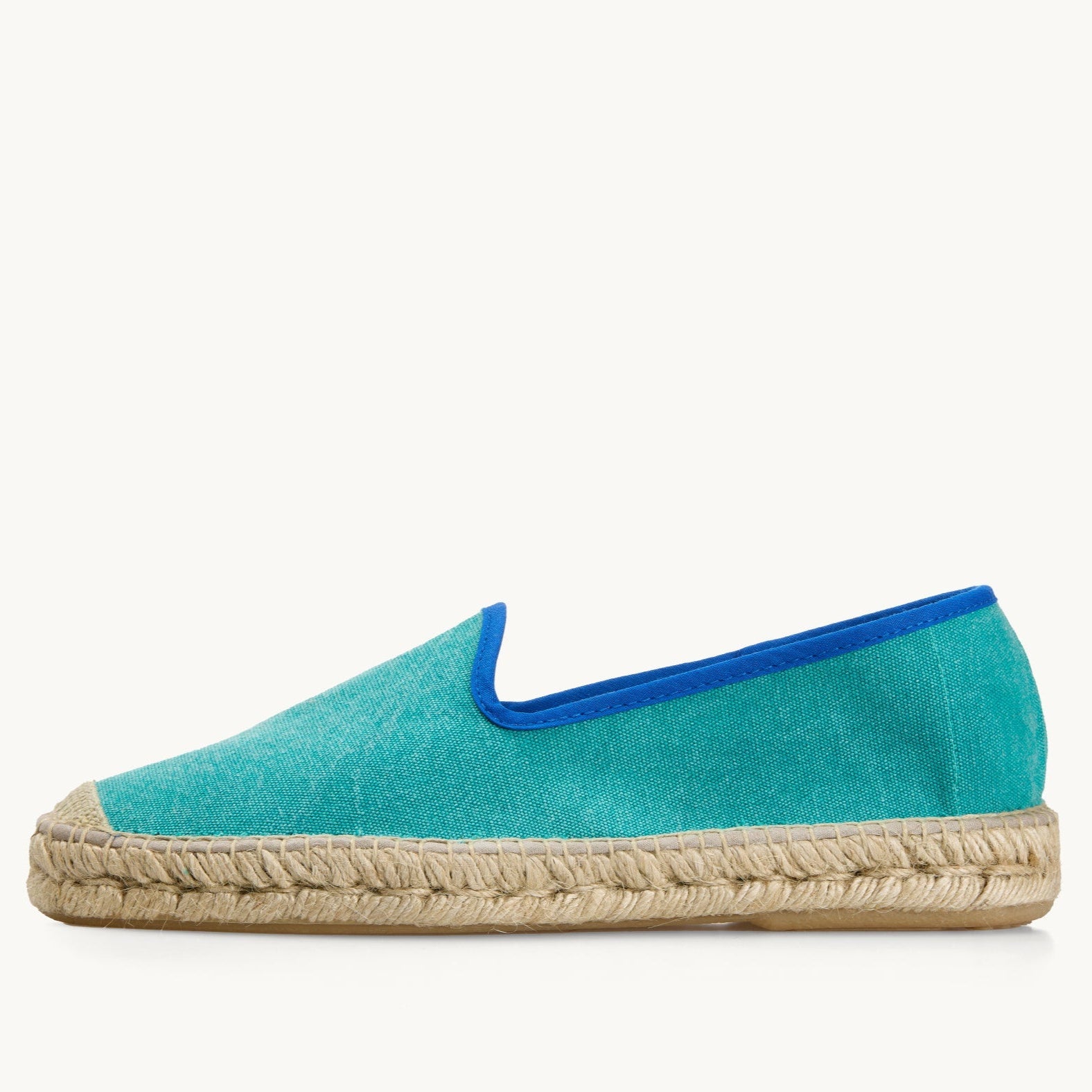 One men's green cotton canvas loafer, side view. Jute sole and detail on the toe. Neck opening of the espadrille has a narrow ribbon edged in royal blue.