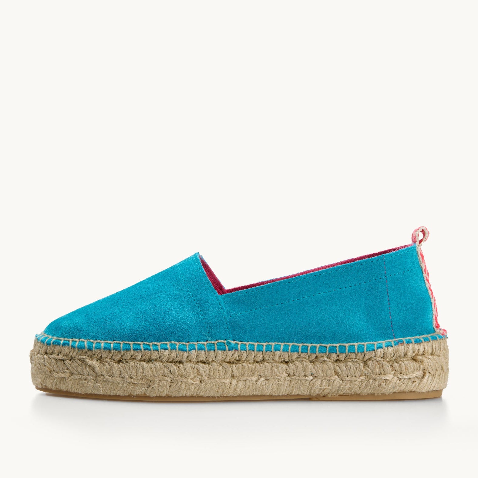 Vibrant turquoise suede platform loafer, side view, edged with bright pink trim inside then neck of the shoe and a neon pink and white patterned ribbon up the heel. The traditional espadrille is stitched to the jute sole.