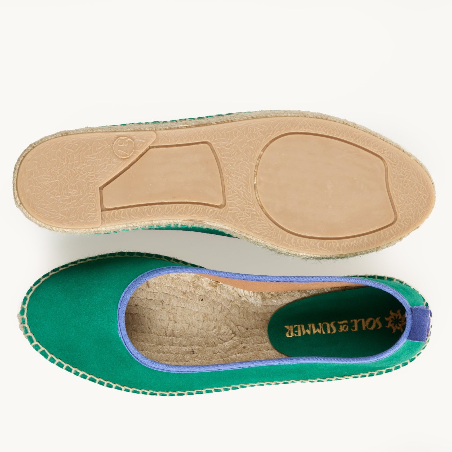 A pair of women's green suede flat ballet espadrilles. One of the shoes is turned over to show the underneath. It has a full rubber covering and the other shoe shows the inner of the footwear, unlined jute insole and the Sole of Summer logo printed inside.