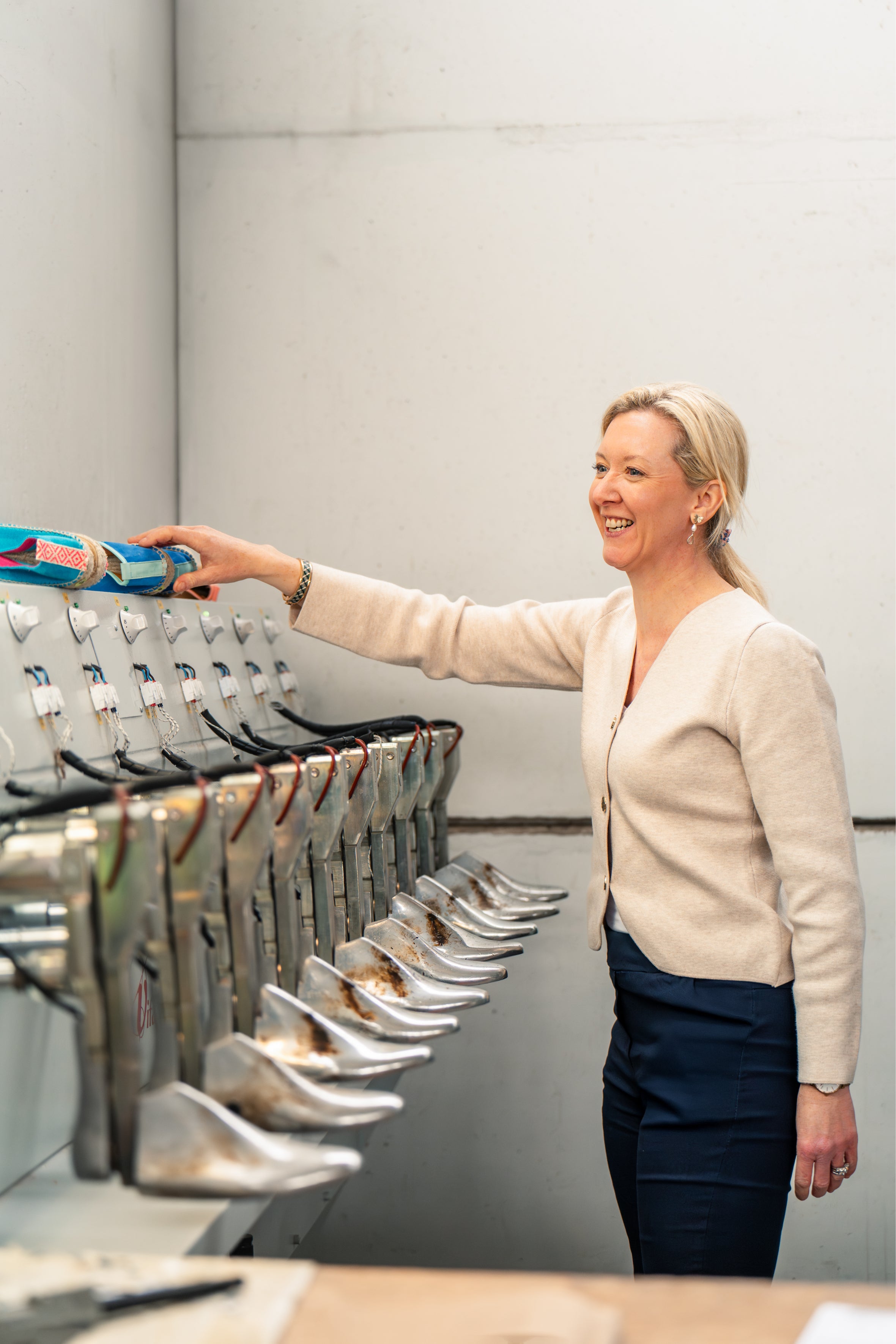 Sarah the owner and founder of Sole of Summer standing in the shoe factory in Spain looking at her espadrilles being made.