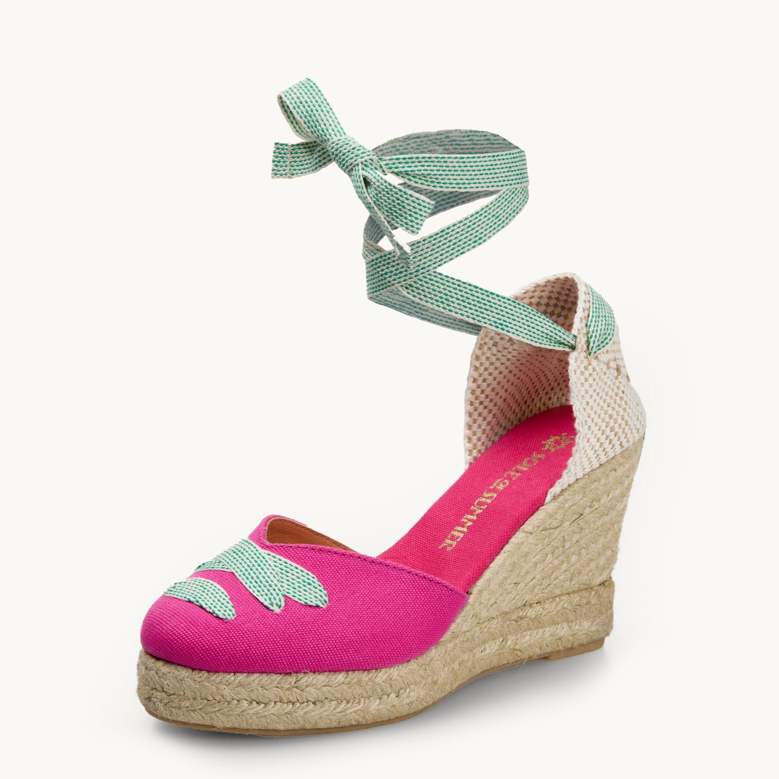 One bright pink cotton wedge espadrille displayed with white and small green dot ribbons tied in a bow as if around an ankle.  The sole is made of Jute. The ribbon detailing is also criss-crossed over the almond shaped toe. The insole is lined in the same pink cotton as the outer of the footwear.