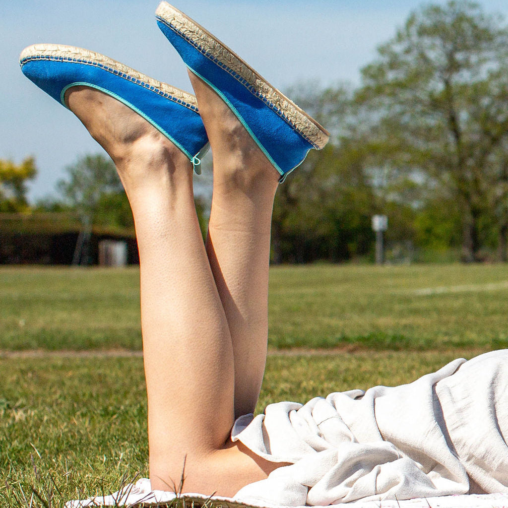 Person wearing blue shoes with jute soles lying on grass