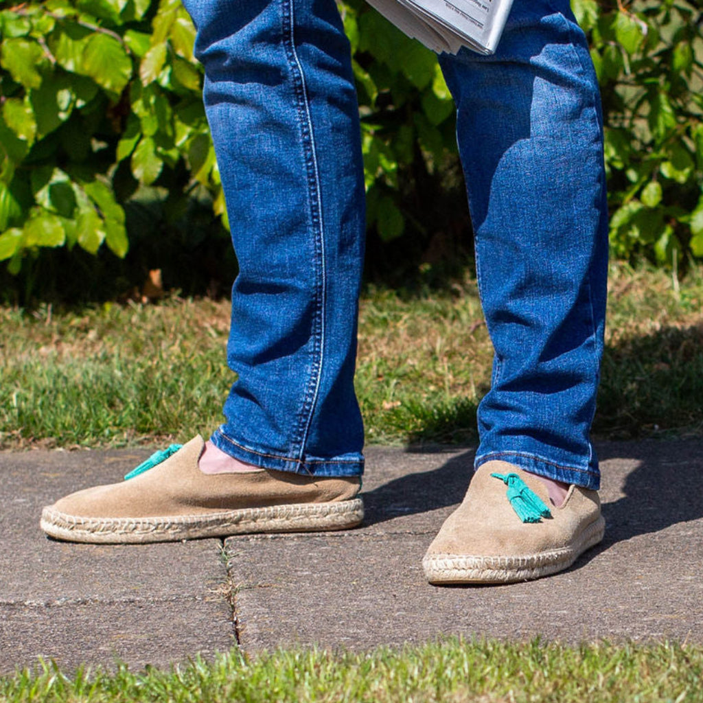 Person wearing denim jeans on a path wearing beige shoes with tassels.