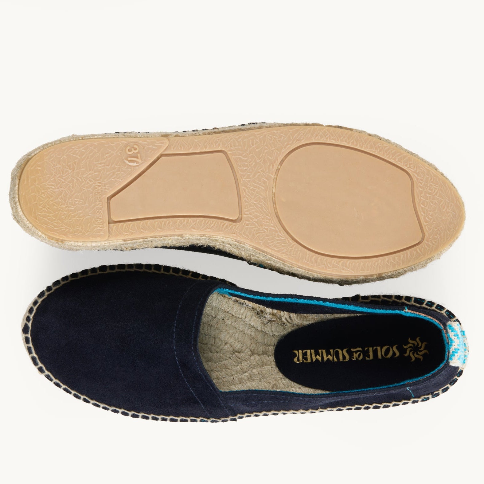 A pair of women's navy blue suede loafer espadrilles. One of the footwear is turned over to show the underneath. It has a full rubber covering and the other shoe shows the inner, unlined jute insole and the Sole of Summer logo.