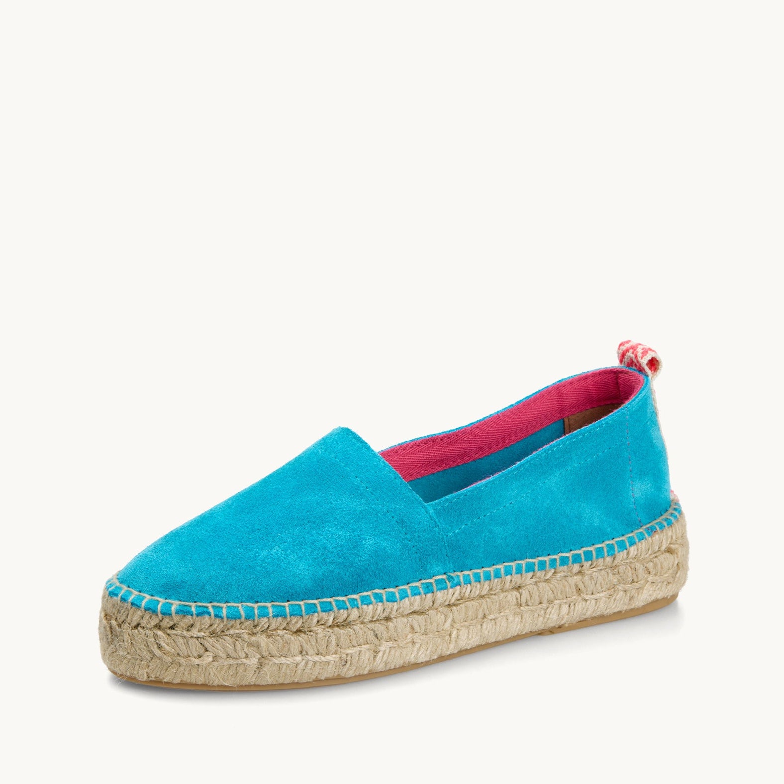 Vibrant turquoise suede platform loafer edged with bright pink trim inside then neck of the shoe and a neon pink and white patterned ribbon up the heel. The traditional espadrille is stitched to the jute sole.
